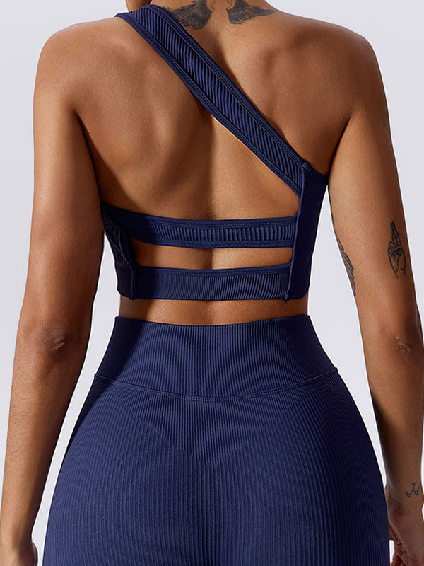 Woman wearing a navy blue one-shoulder sports bra, showing breathable nylon fabric design for fitness activities.